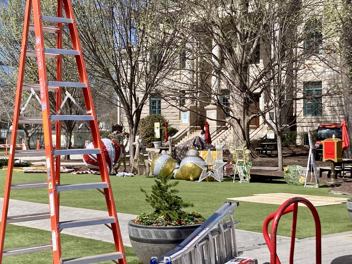 The city of Decatur square with ladders and equipment in the foreground and giant Christmas ornaments in the distance.