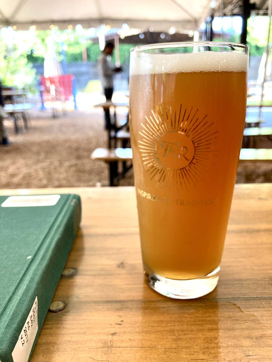 A beer and a book on a table in a beer garden.