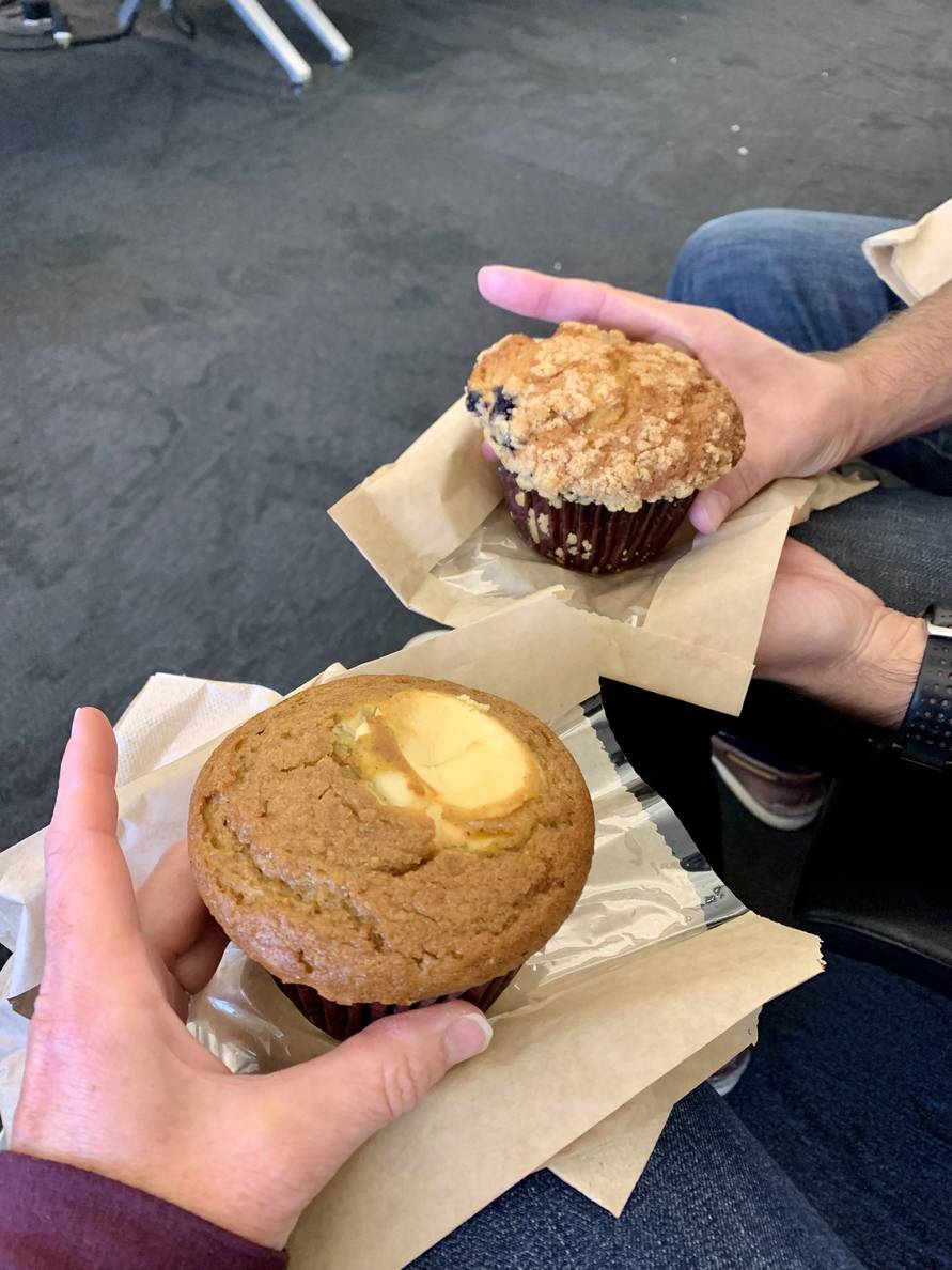 Two people holding muffins on top of napkins.