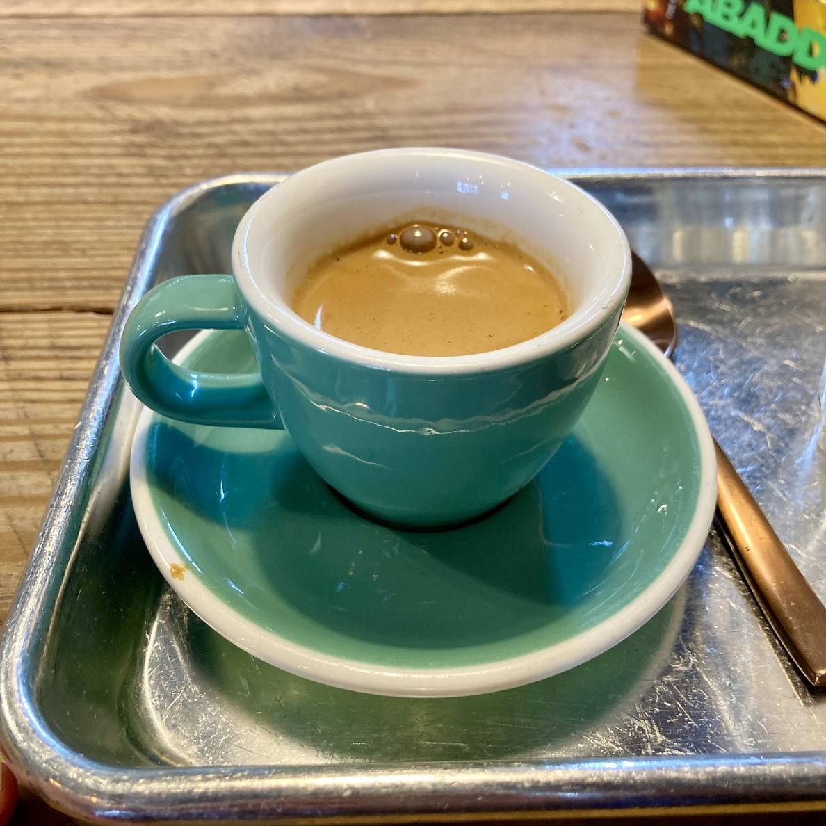 An espresso on a saucer on a tray.