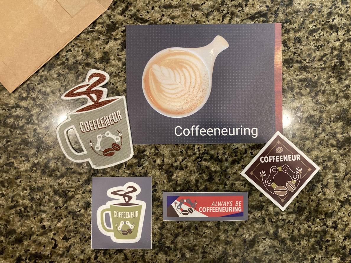 A selection of stickers with coffee and cycling motifs. One reads “always be coffeeneuring.”