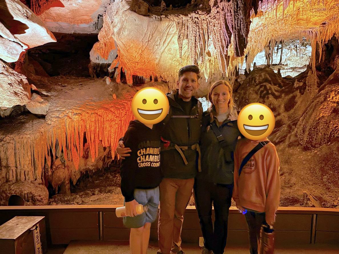 A family stands in a cave. Stalactites in the background.
