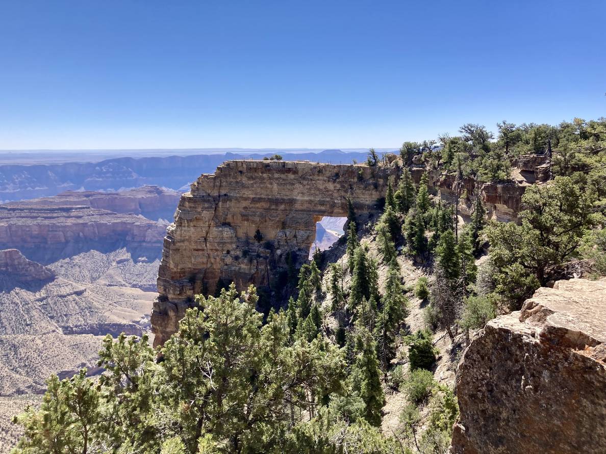 A rocky point extends into the Grand Canyon. An opening is in the middle of the point, like a window.