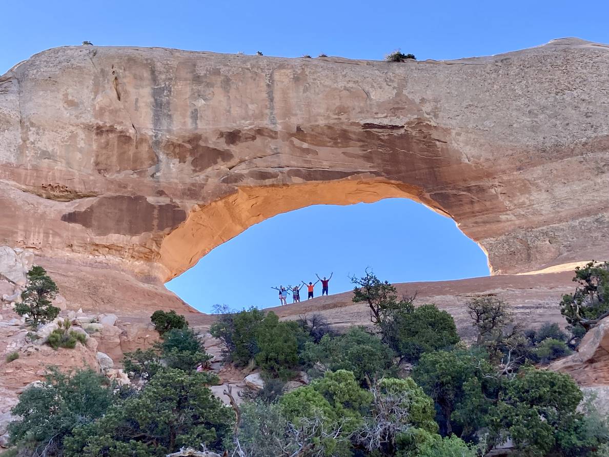 People stand within a large stone arch. In comparison, the people are minuscule.