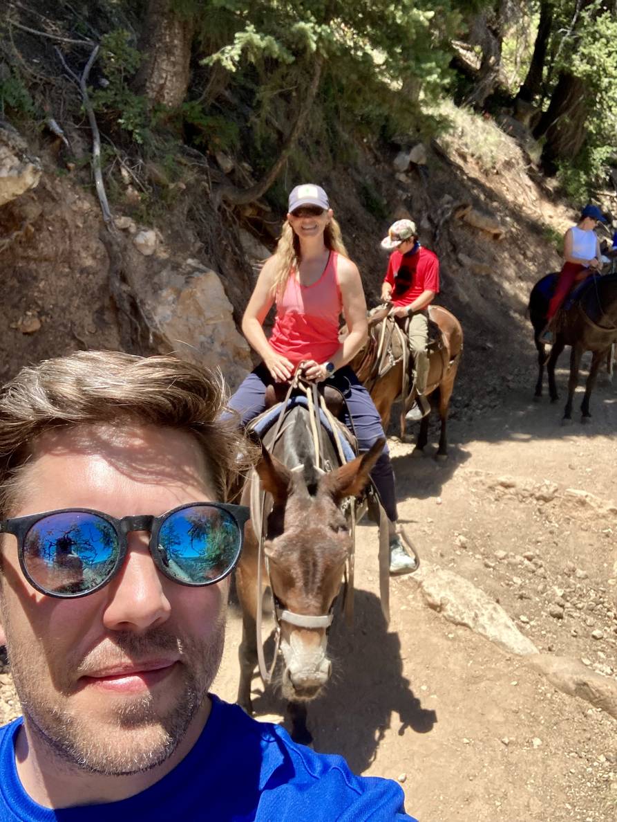 A selfie of a man with a people on mules behind him.