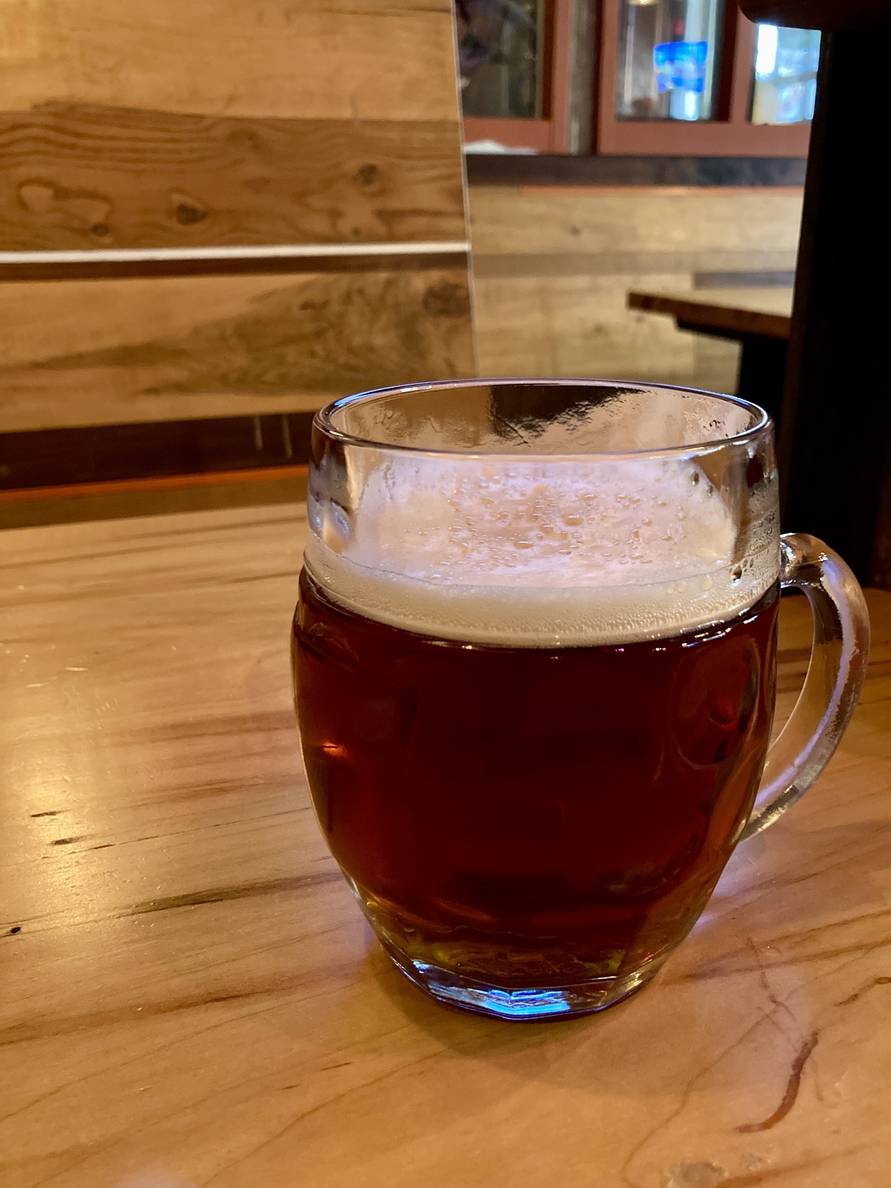 A glass of beer on a wooden table.