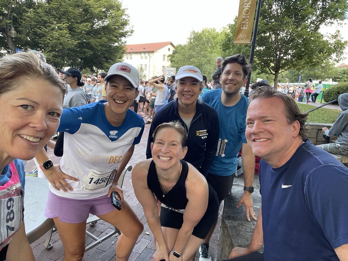 A group of people in running clothes with a crowd of runners behind them.