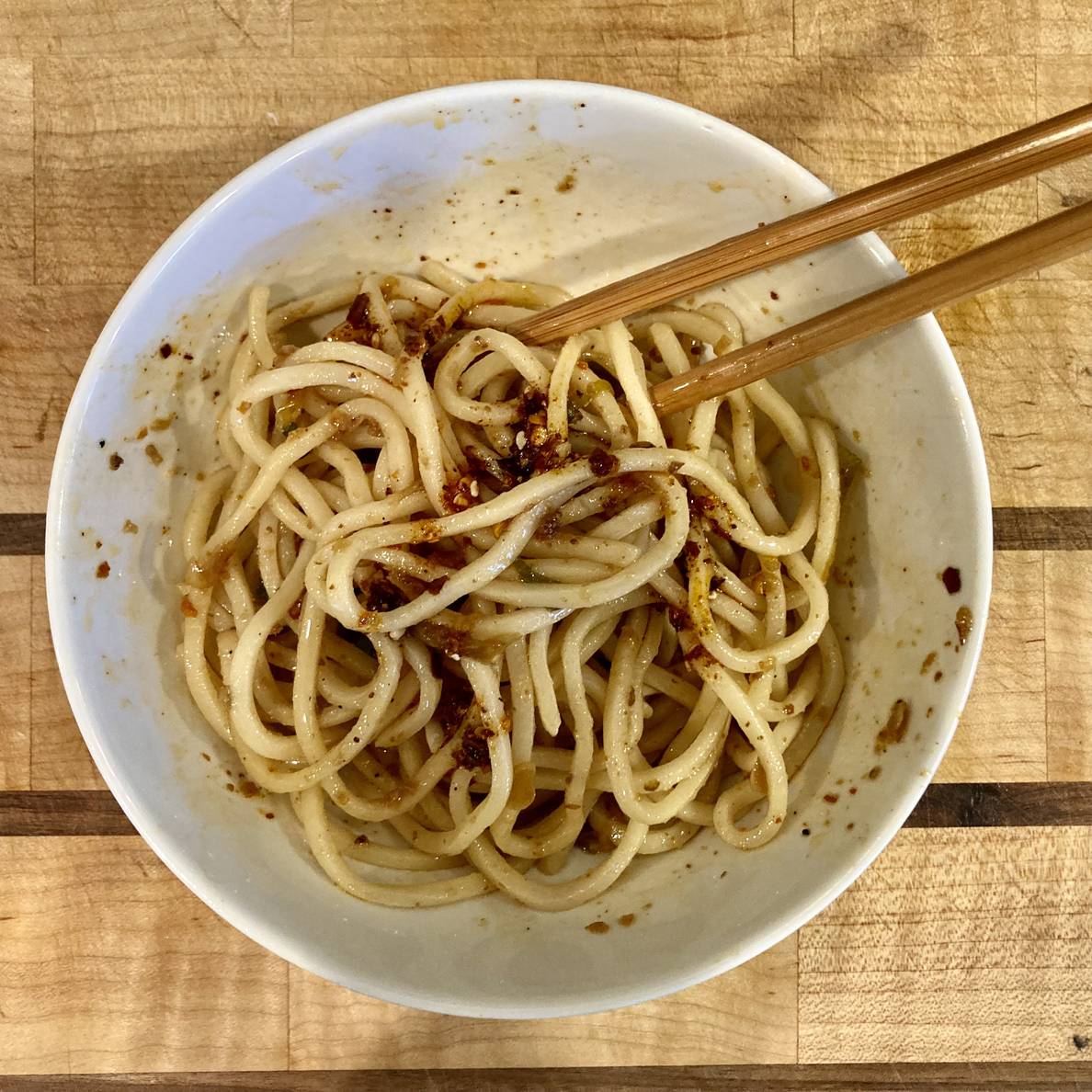 A bowl of noodles with chopsticks.