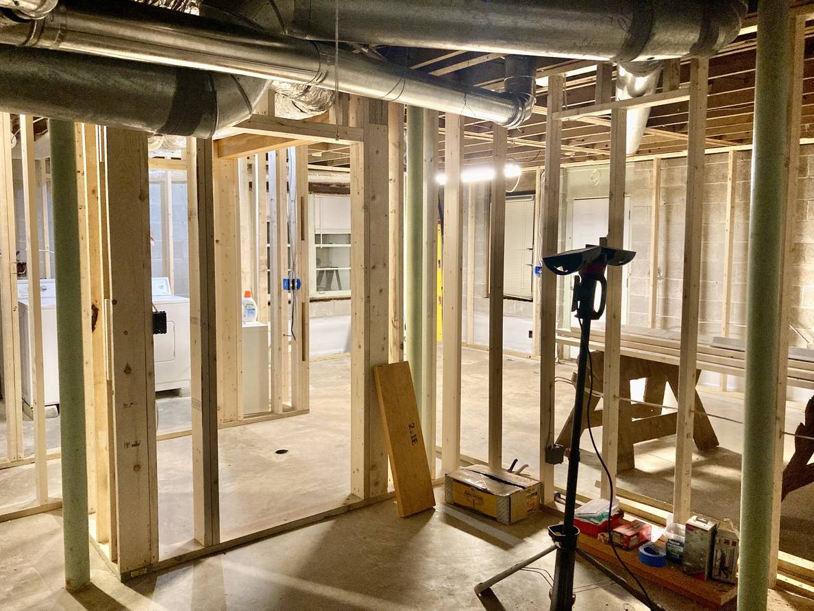 A basement with framed walls. Duct work is along the ceiling.