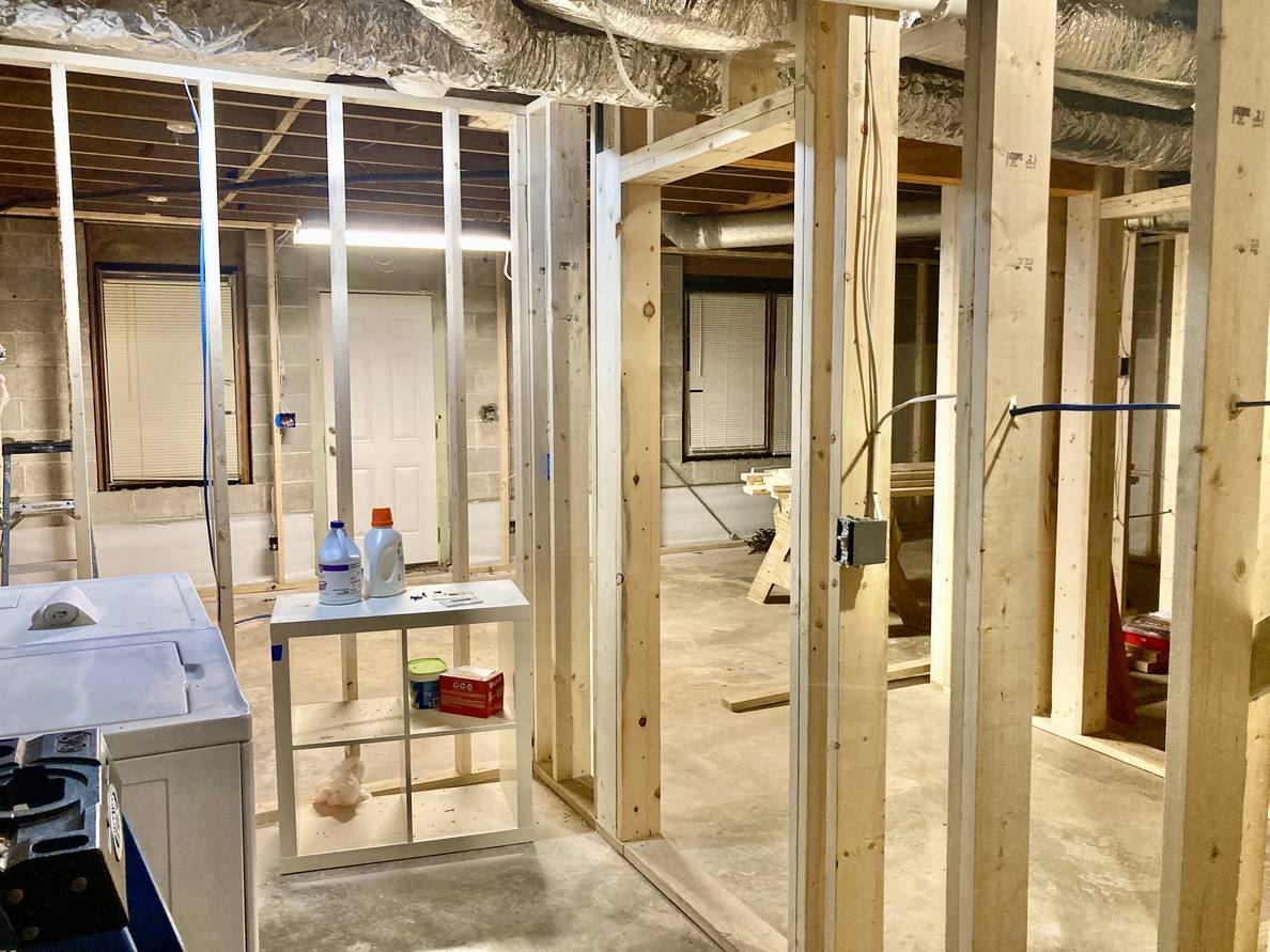 A basement with framed walls. Laundry machines are visible in the foreground.