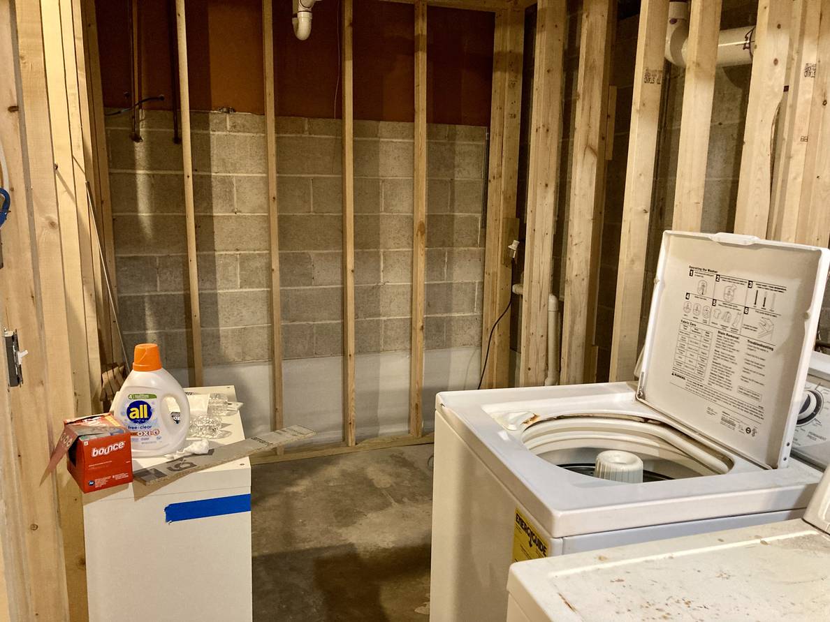 The unfinished laundry room. The walls are framed out and the laundry machines are pulled away from the walls in preparation for the spray foam insulation.