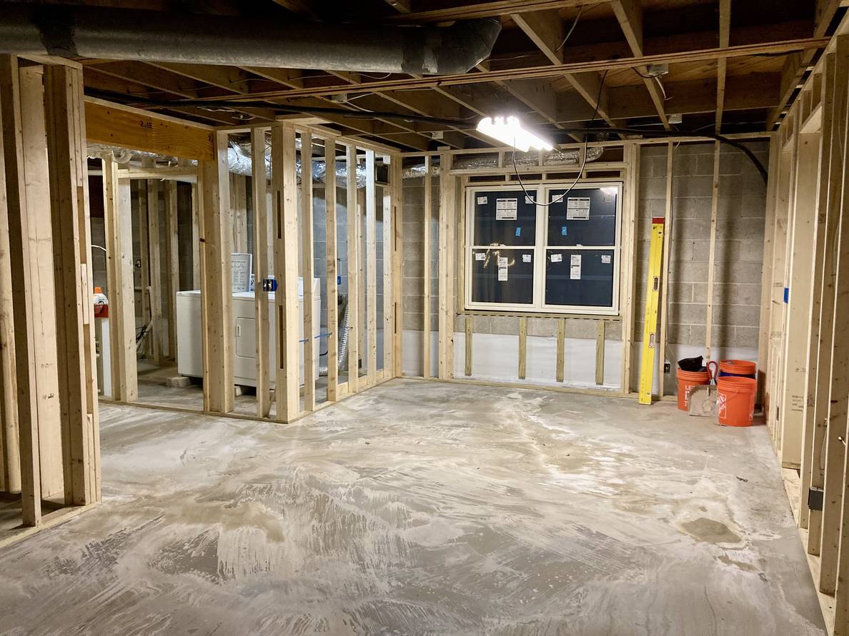 The same main space. From this angle another wall with a new window is seen. The alcove that leads to the stairs is also visible, and the laundry space beyond the far wall.