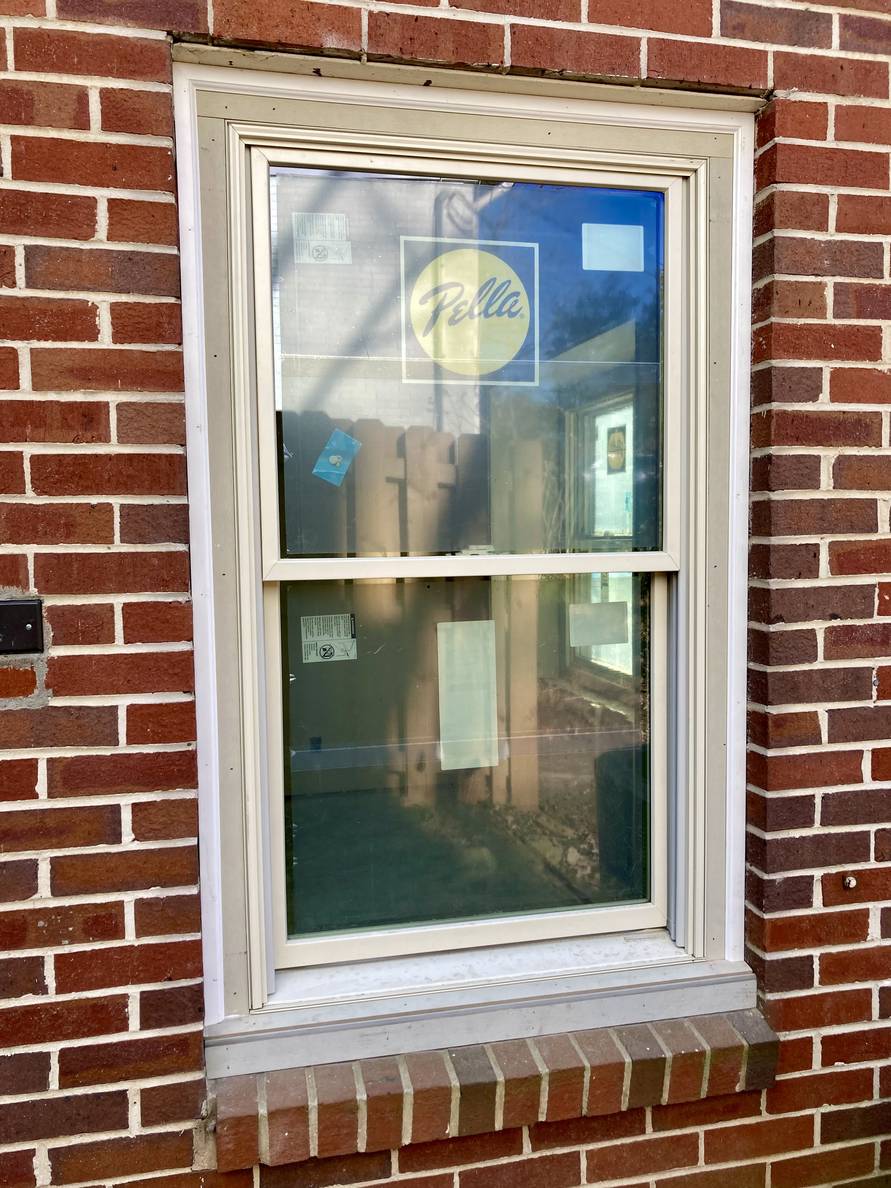 A photo of the outside of a house window. The window trim is unpainted.