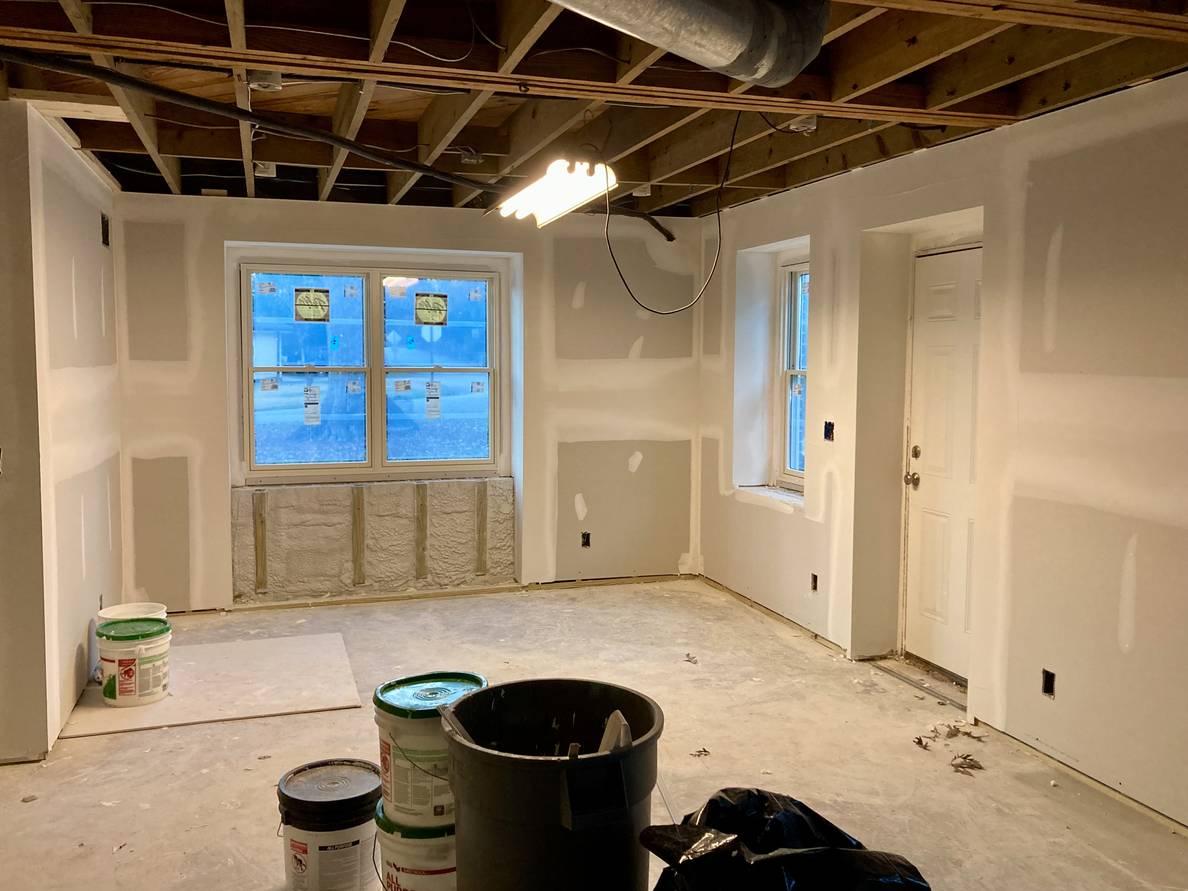 A photo of a partially finished basement. The seams of the drywall and various additional patches have drywall compound.