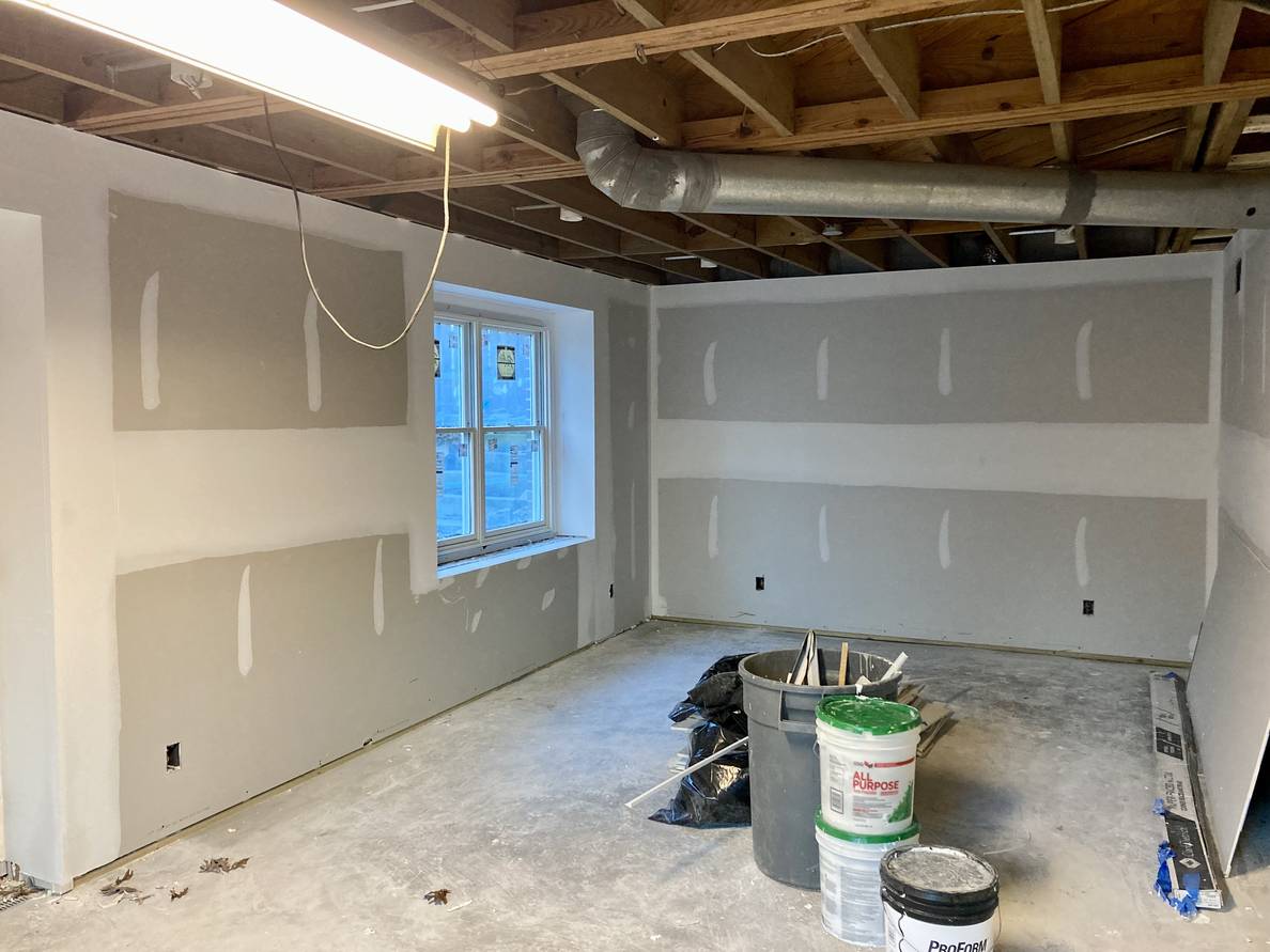 A photo of a partially finished basement with mudded drywall.