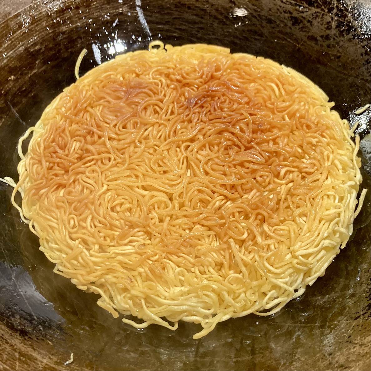 A photo of the noodle cake showing the first cooked side.