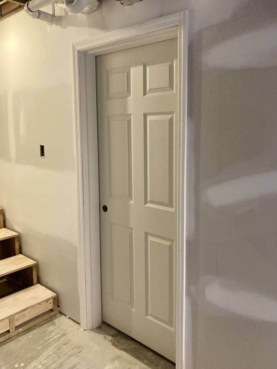 A photo of a partially finished basement doorway with a newly hung door.