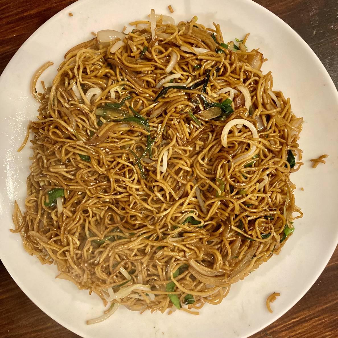 A photo of the finished dish of Cantonese Superior Soy Sauce Noodles. It’s mostly an homogeneous plate of noodles with bits of bean sprouts, onion, scallion, and Chinese chives visible.