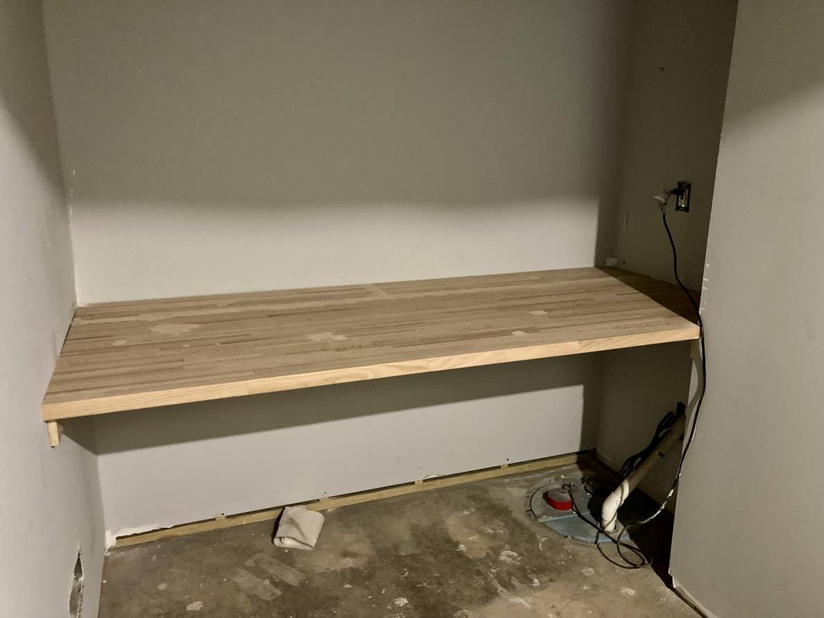 A photo of a partially finished room with a butcher block shelf spanning the length of the end wall.