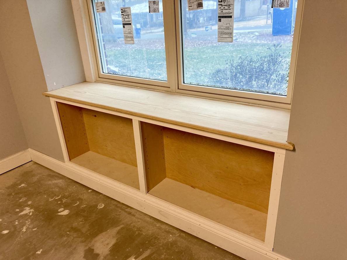 A photo of a deep set window. Below the window are the shelf frames, but the middle shelf is not yet installed nor is it fully trimmed out.