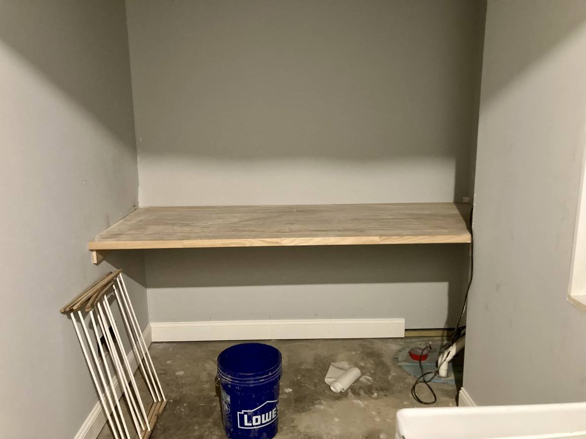 A photo of the partially finished laundry room. Along the far wall is a deep butcher block shelf.