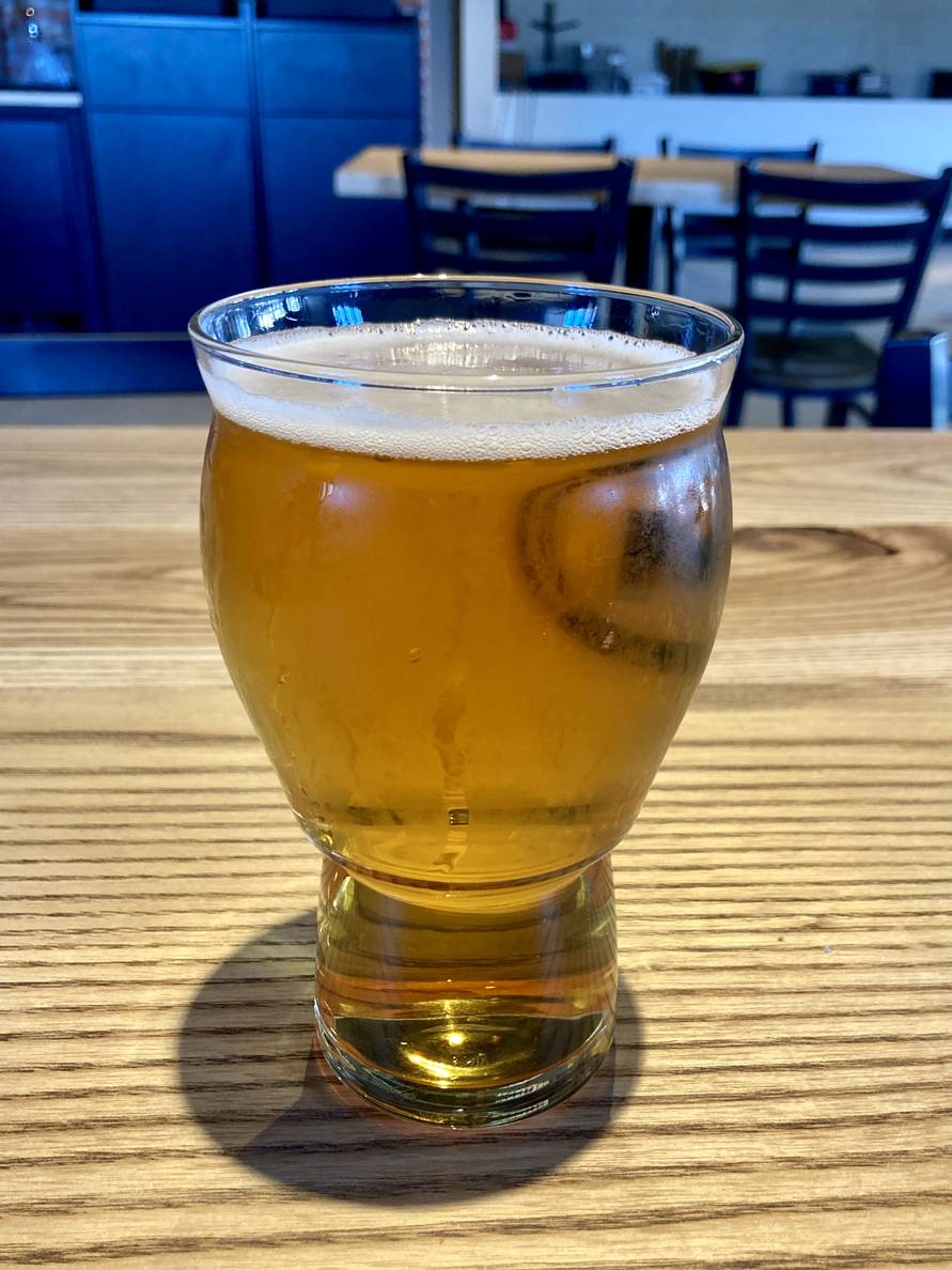 A photo of a glass of beer on a wooden table.