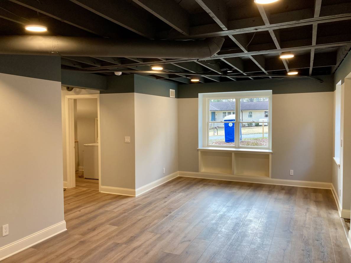 Another photo of the same basement space from a third angle. From this angle a built in bookshelf below a double window is visible.