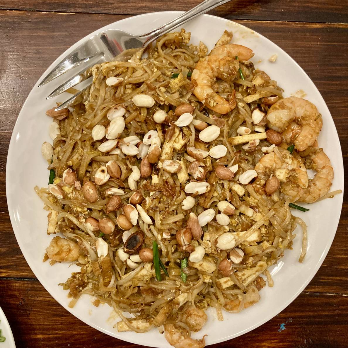 A photo of a plate of pad Thai. The top is sprinkled with peanuts, and some shrimp are visible among the noodles.