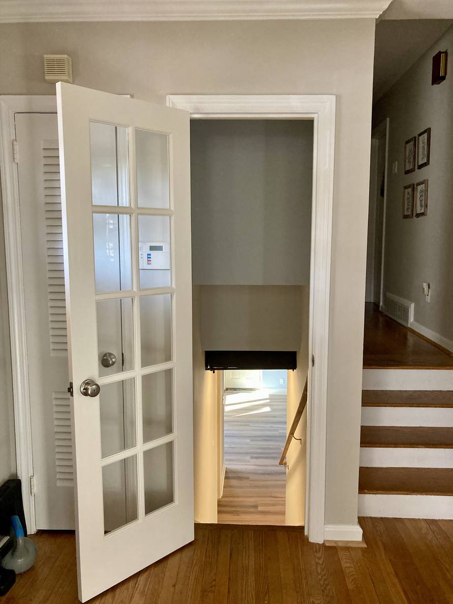 A photo of the door to the basement from the main floor. The door is open and the lights are on in the basement.