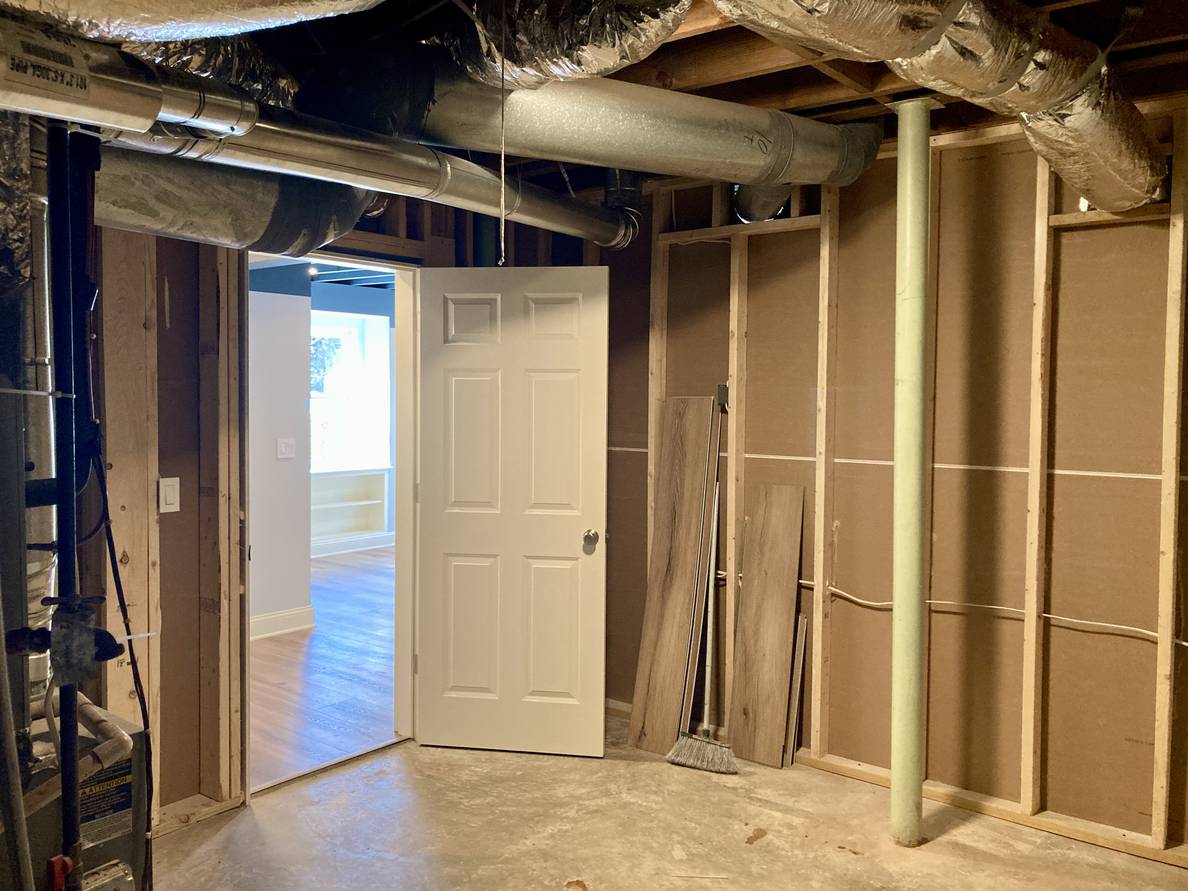 The after photo from this corner. This position is now in the utility room. A door opens into it and the backs of the walls of the finished space enclose it. One of the remaining metal support poles can be seen.