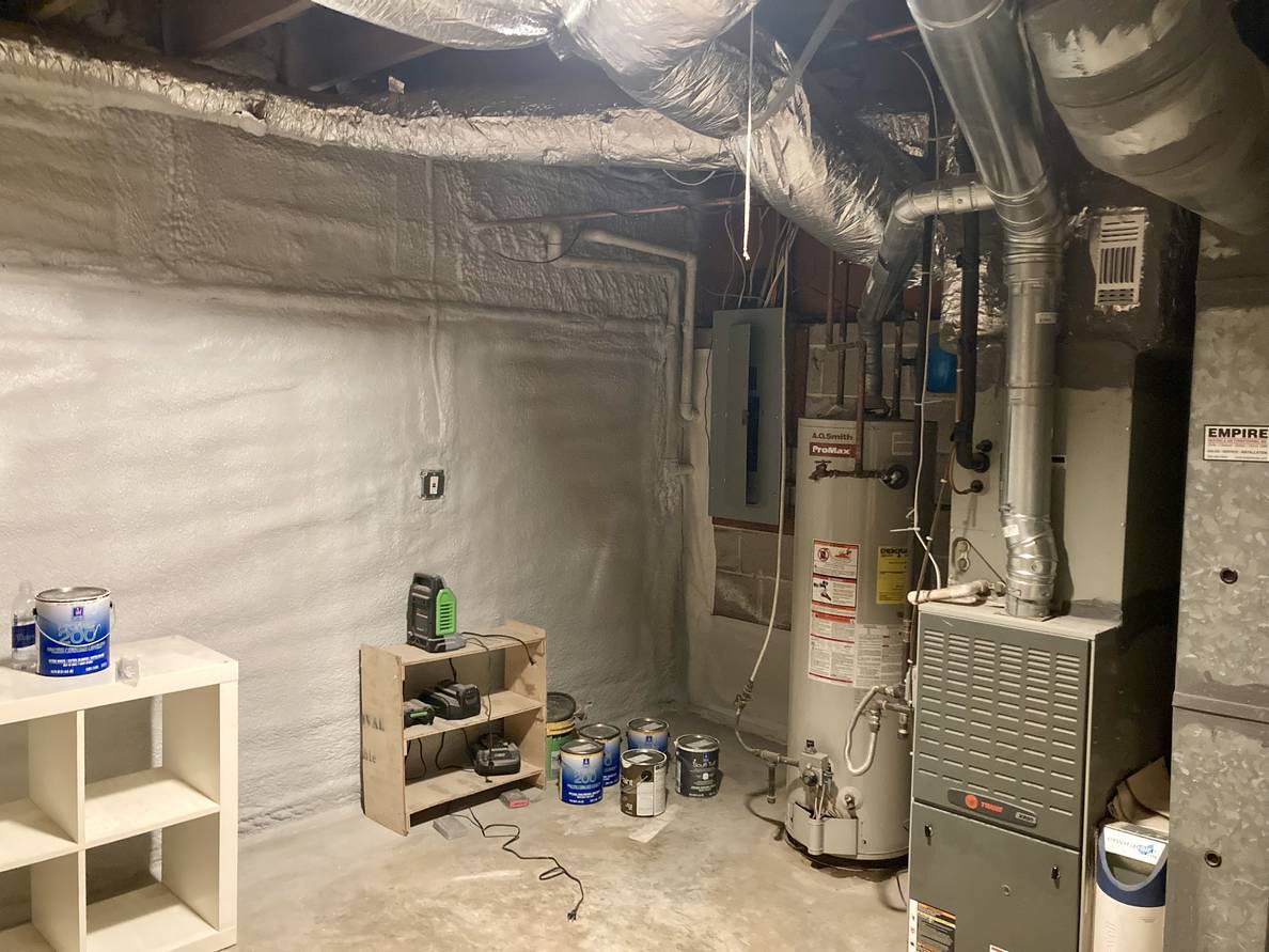 A photo of the changed, but still unfinished, utility room. The newly insulated exterior wall is visible as well as the HVAC and water heater.