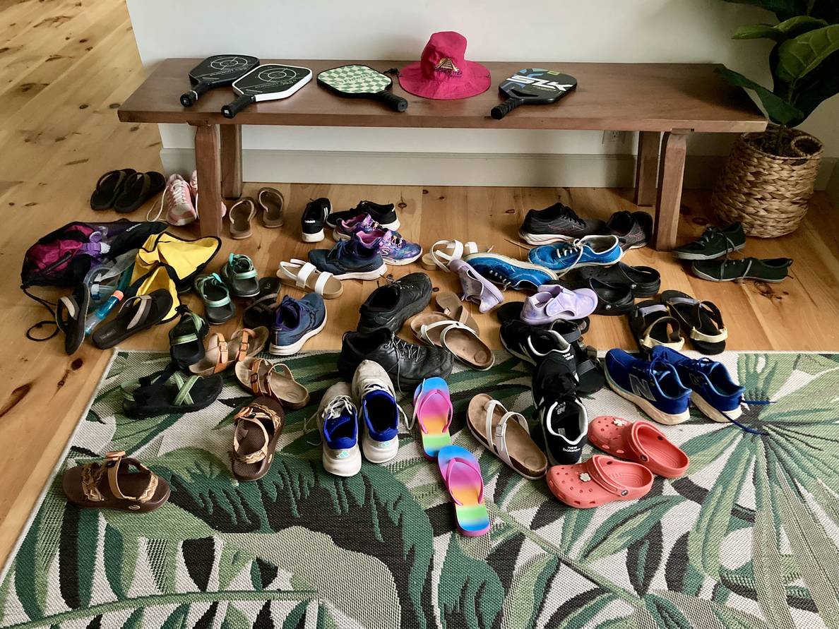 A bunch of shoes on the floor at the entrance to a house