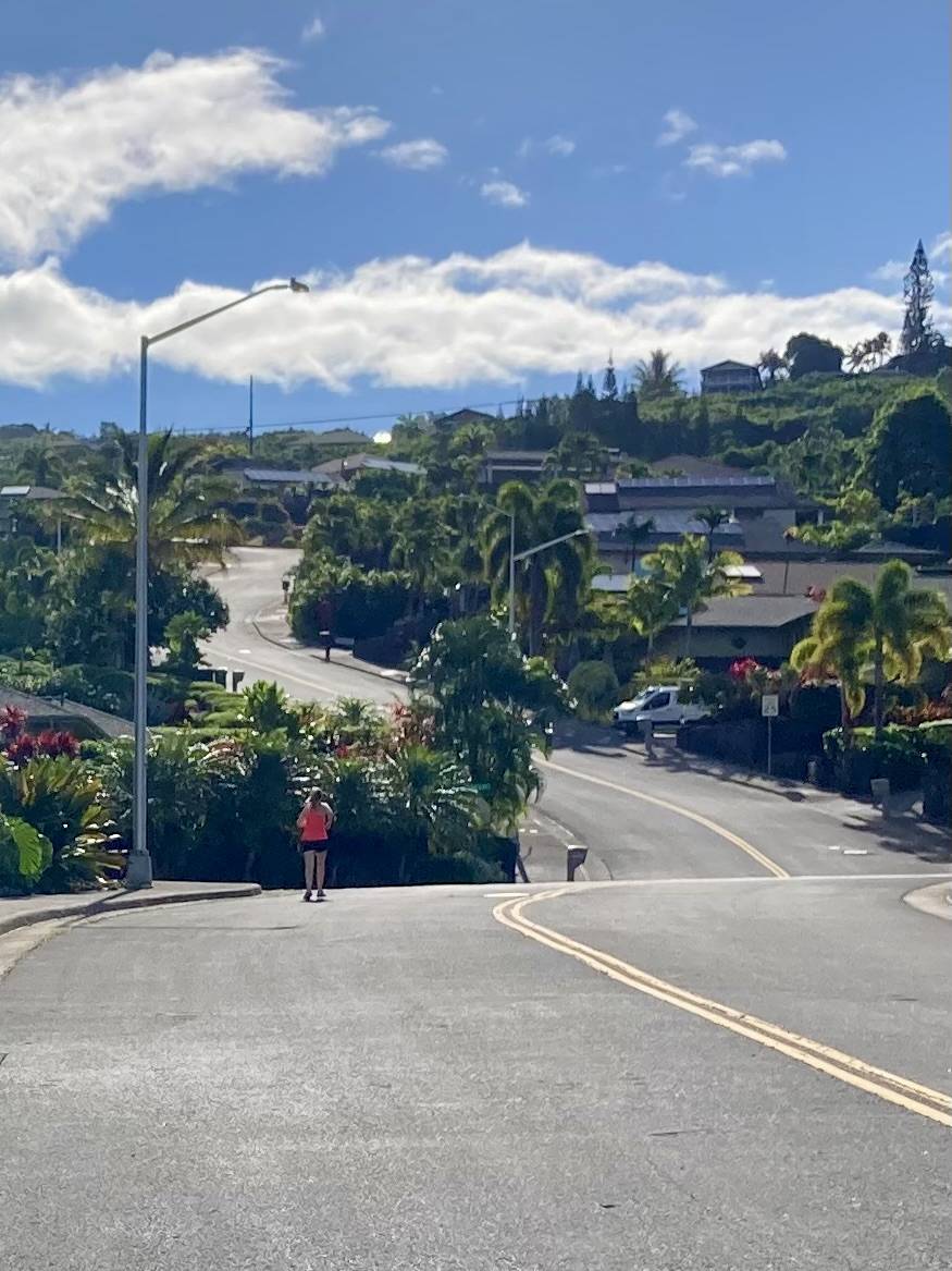 A photo of Megan running up a steep road in Hawai’i