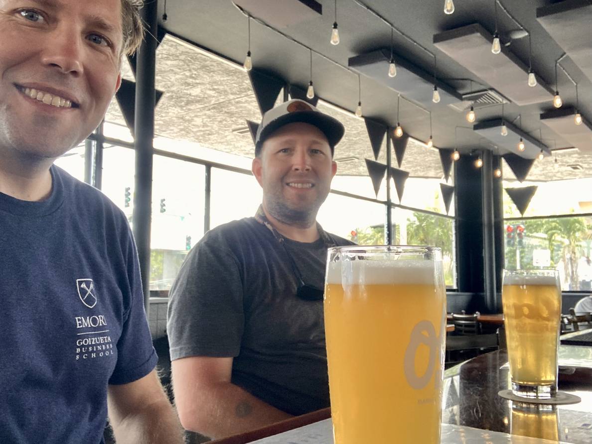 A photo of two men with beers at a bar