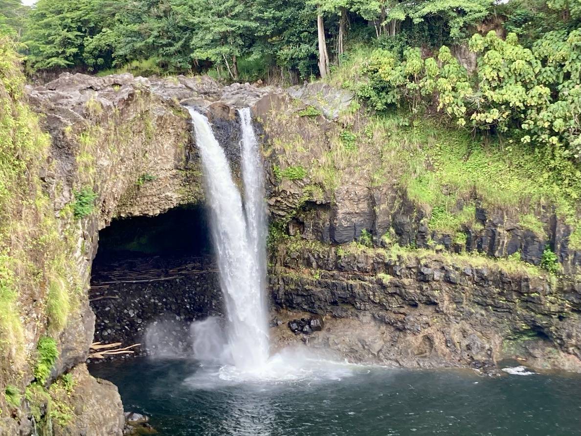 A photo of Rainbow Falls falling over a cave into a pool of water.