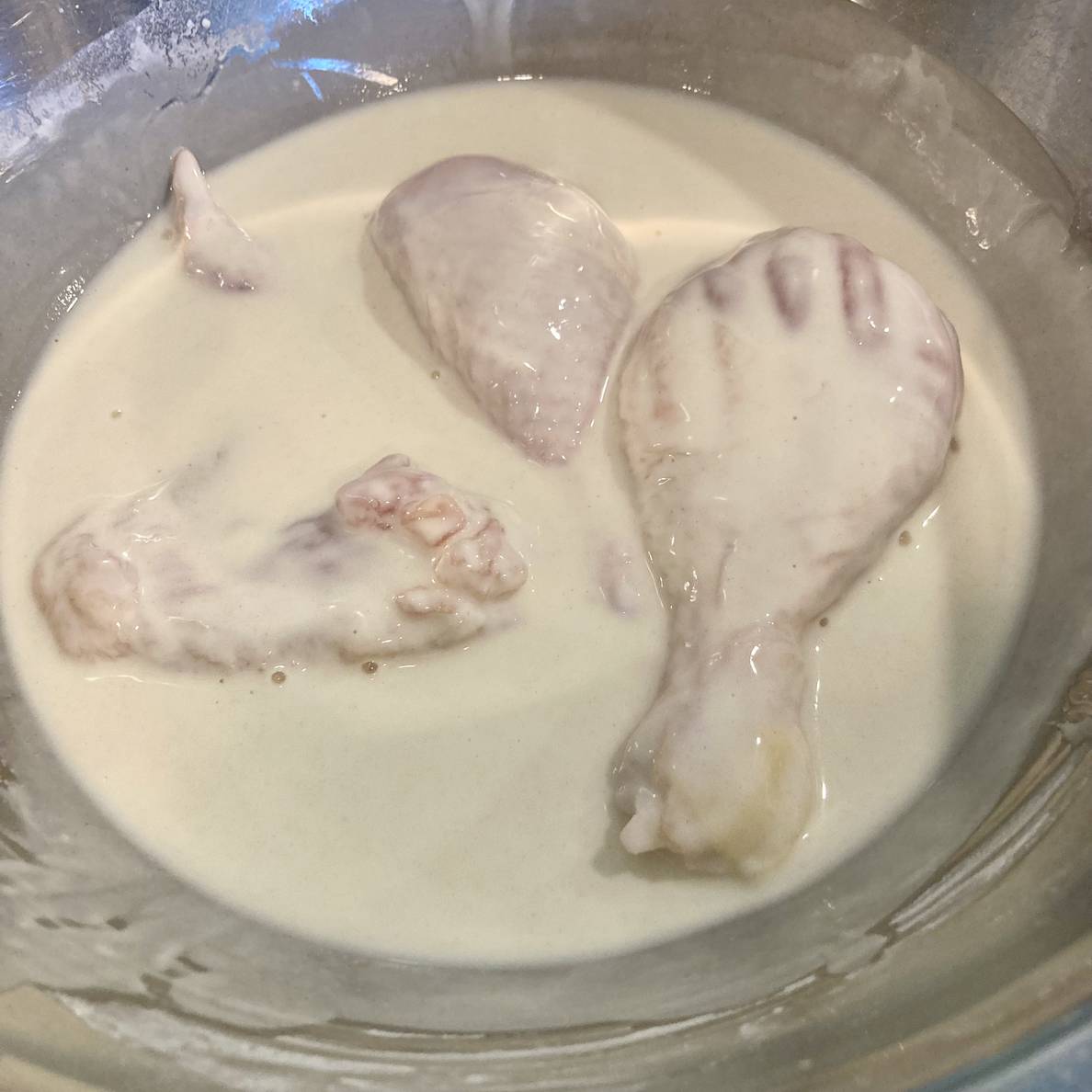 A photo of a few pieces of chicken in a bowl of the thing batter.