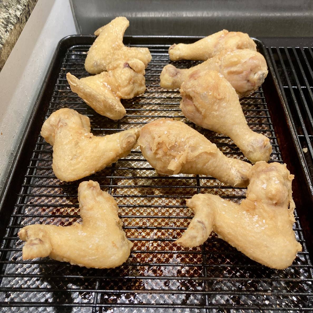 A photo of the fried chicken on a wire rack in a sheetpan.