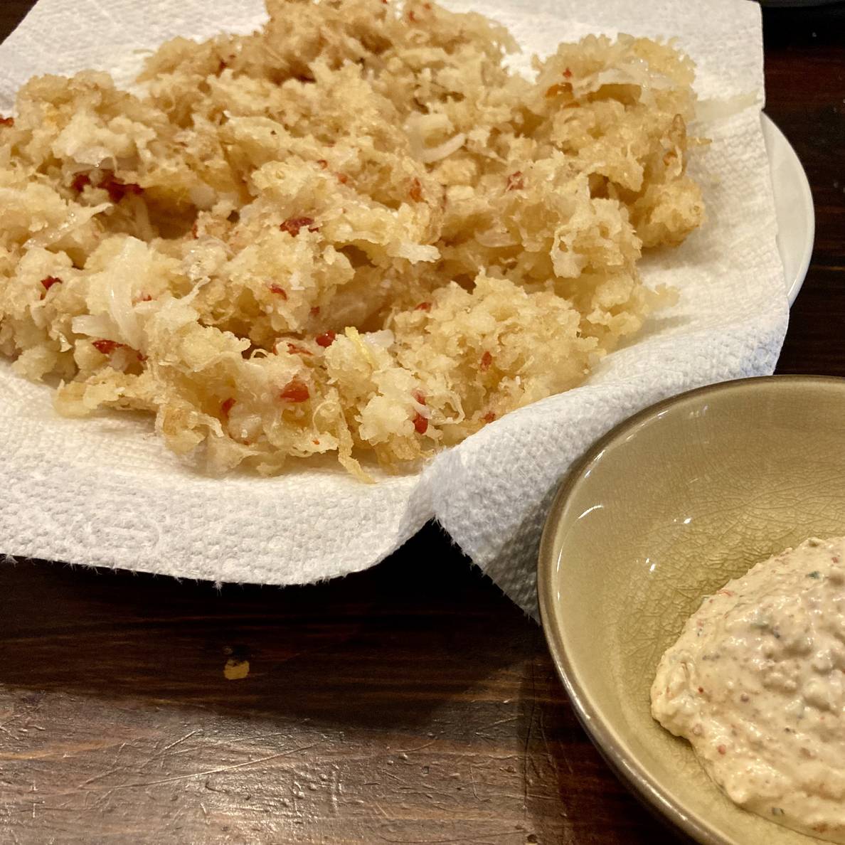 A photo of a plate of tempura-fried sauerkraut, onions, and chiles, with a side bowl of gochugaru yogurt ranch dressing.