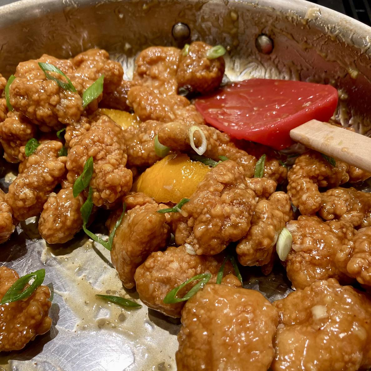 A photo of the finished orange chicken in a pan on the stove.