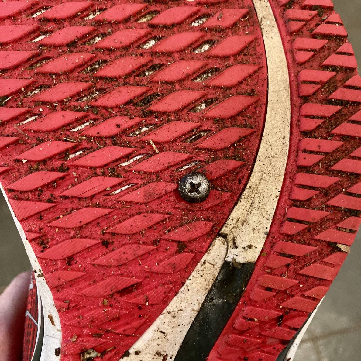 A photo of the bottom of a running shoe with a small screw embedded in it