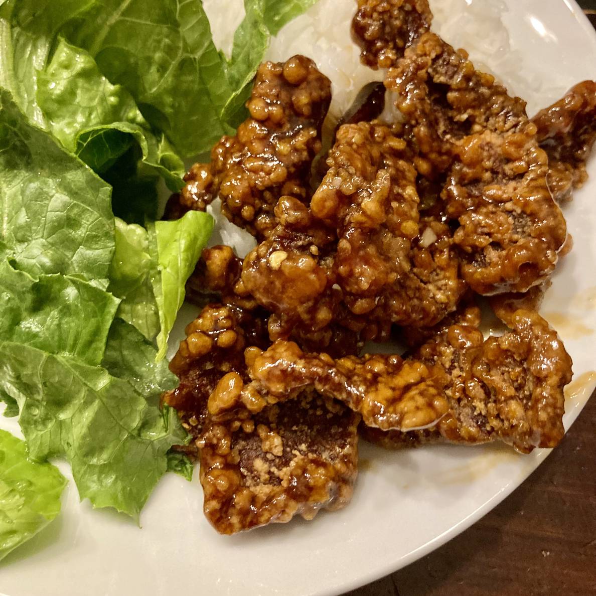 A photo of the finished orange peel beef on a plate with rice and salad.