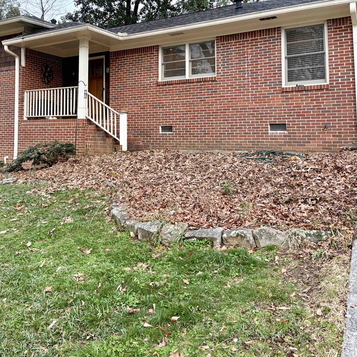 A photo of the front entry bed after removing the shrubs. What was once full of bushes blocking the view of the walkway is now empty.