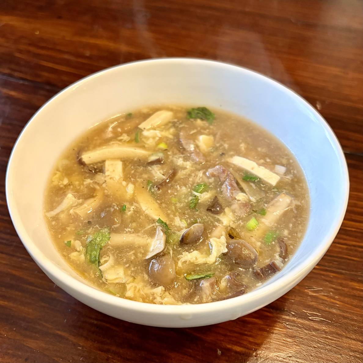 A photo of the finished soup in a bowl. It is full of mushrooms and tofu and eggy bits.