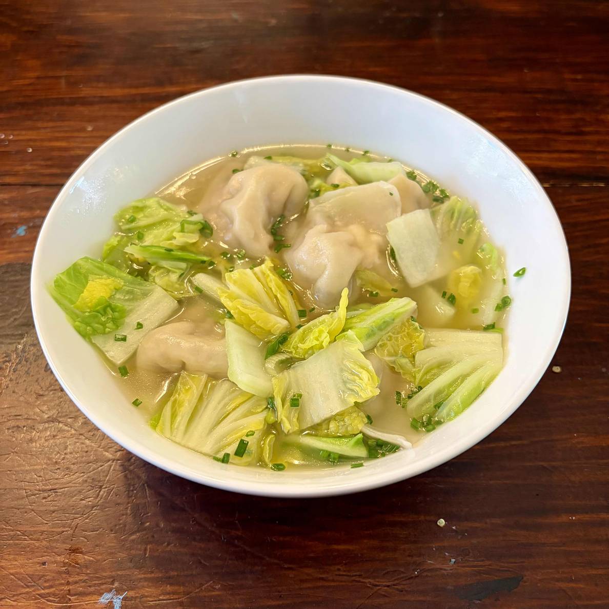 A photo of a bowl of the wonton soup. It is chock-full of wontons and cabbage.