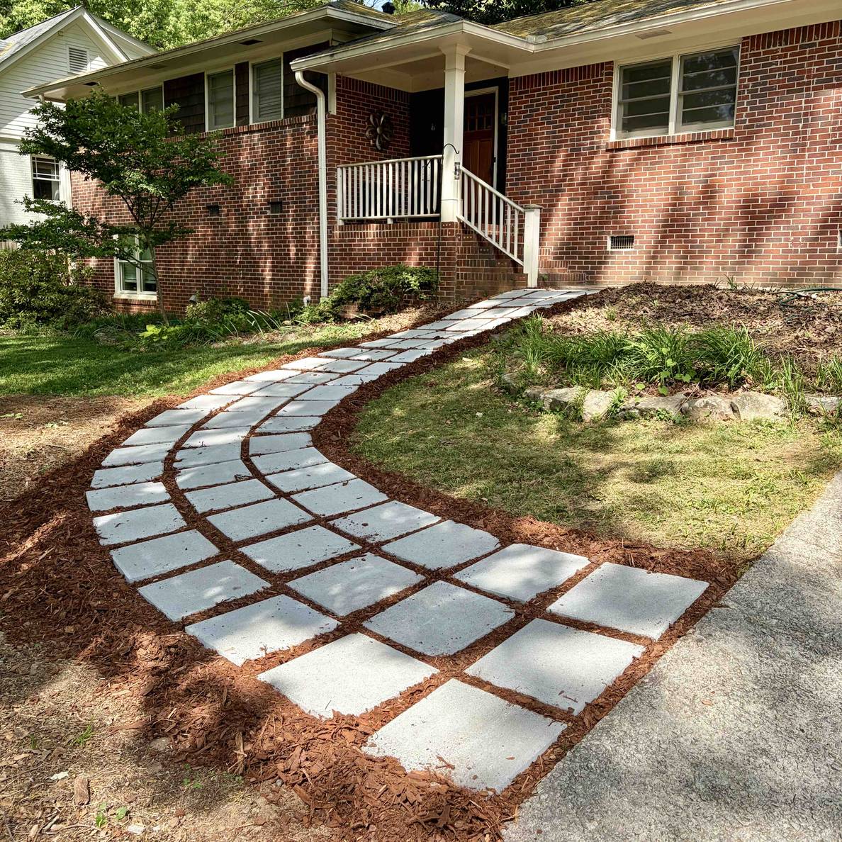 A photo of the front entry with the newly laid paver walkway curving from the driveway to the front porch steps.